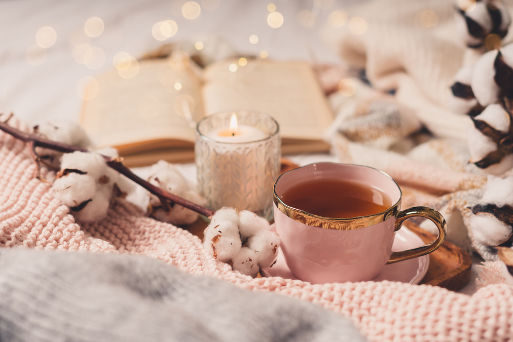Cup of tea, cotton, cozy, book, candle. Cosy autumn winter concept.